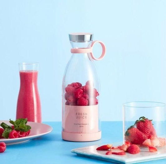 Glass bottle with pink base and silver top, filled with raspberries, on a blue background with a glass of pink juice and strawberries.